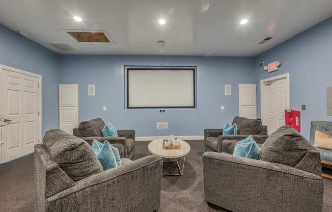 A living room with grey couches and a white screen.