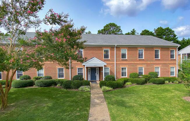 a house with a lawn in front of a brick building