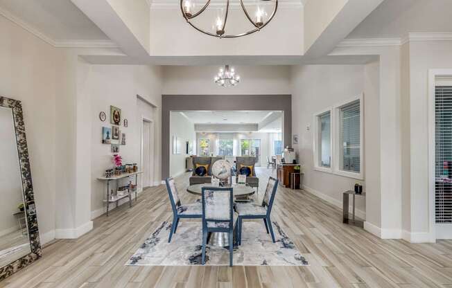 A dining room with a table set for four and a chandelier hanging from the ceiling.