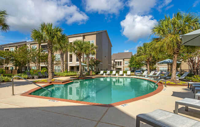 a swimming pool with palm trees and a building in the background at Summerwind, Texas, 77584