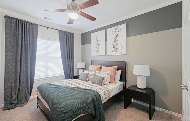 A bedroom with a bed, nightstands, and a ceiling fan.