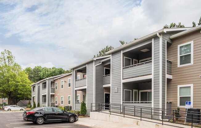 A black car is parked in a parking lot in front of a building.