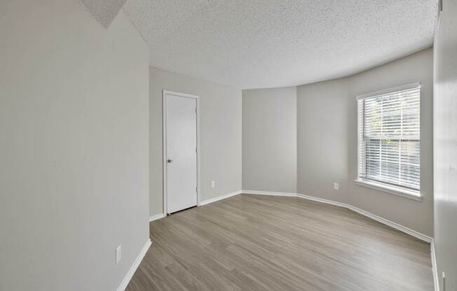 A room with a door, window, and wooden flooring.
