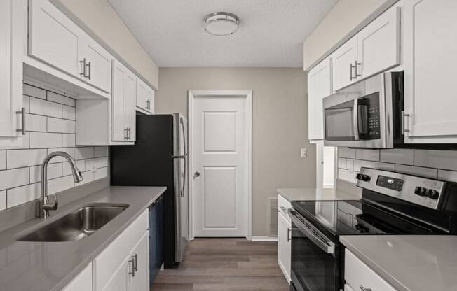 an empty kitchen with white cabinets and black appliances