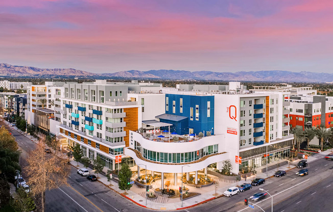A large hotel with a blue and white building in the foreground and mountains in the background.