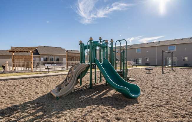 a playground with slides and sand in front of a building