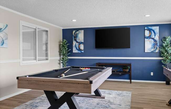 A pool table in a room with blue walls and a flat screen TV.