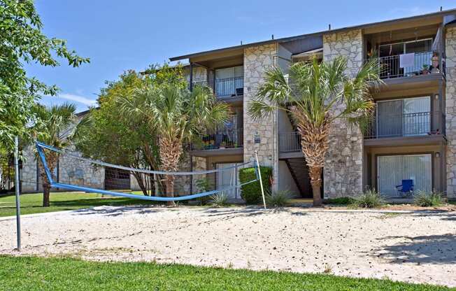 an apartment building with a sandy beach and palm trees