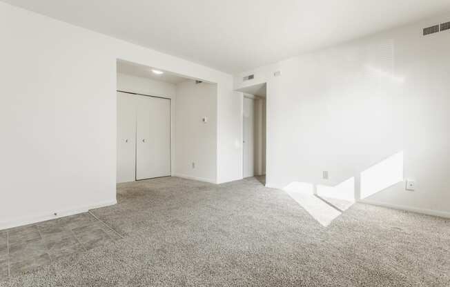 an empty living room with white walls and tile floor