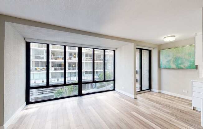 an empty living room with a large window and hardwood floors