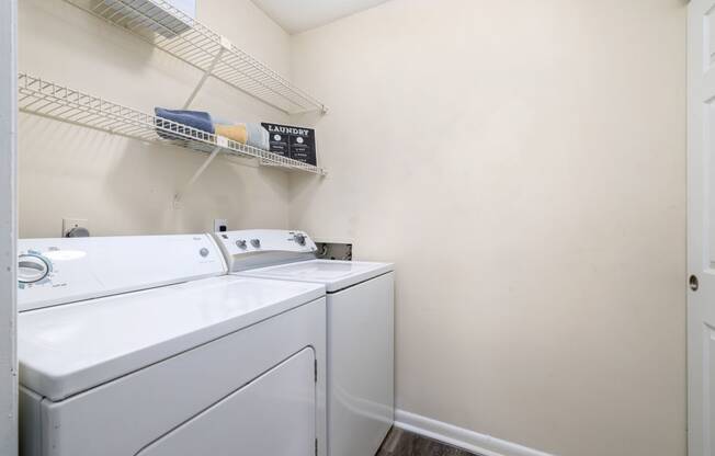 a washer and dryer in a laundry room with white walls and white appliances