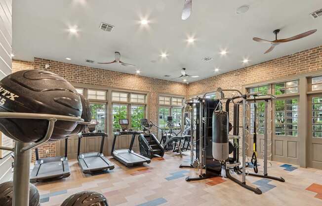 A gym with a variety of equipment including treadmills, a punching bag, and a weight machine.