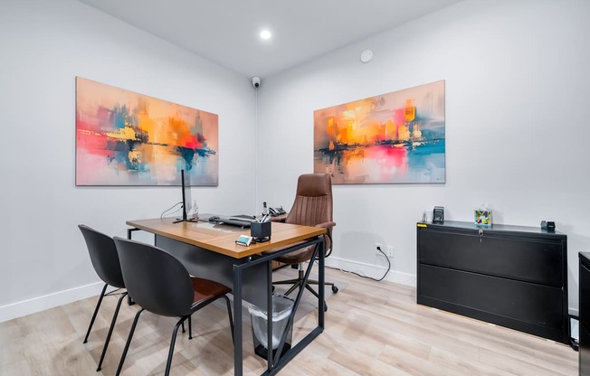 A room with a table and chairs and two paintings on the wall.