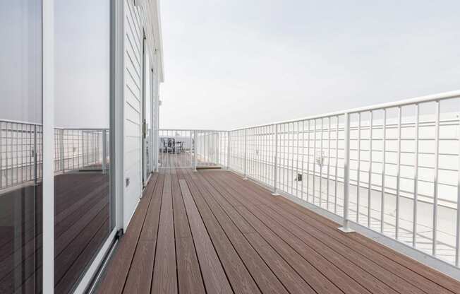 a balcony with a wooden floor and a white metal railing