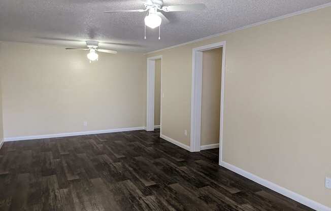 an empty living room with wood flooring and a ceiling fan