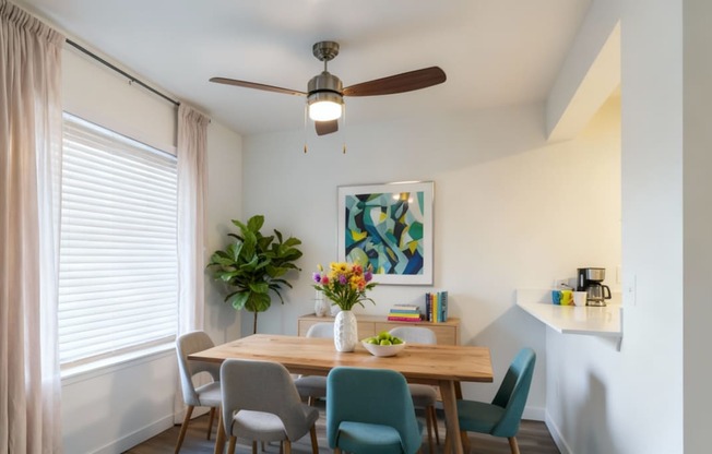 A dining room with a table set for two and a ceiling fan.