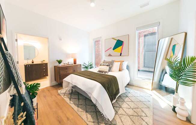 A bedroom with a bed, nightstand, and a mirror.