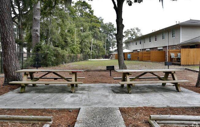 two picnic tables in a park in front of a building