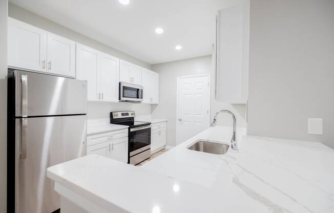 a white kitchen with stainless steel appliances and white counter tops