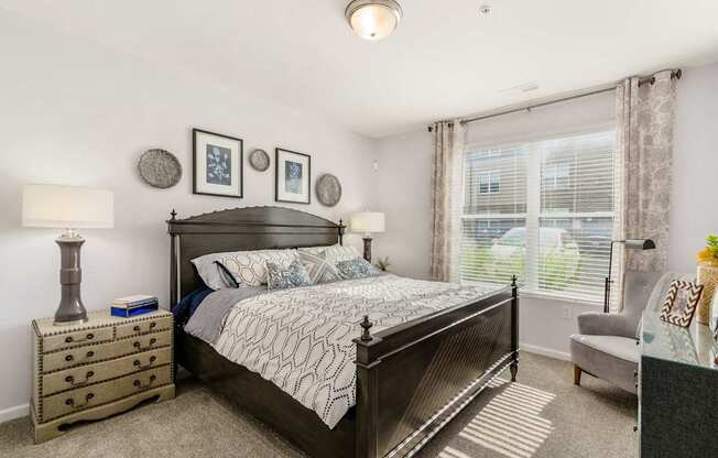 A bedroom with a large bed, a nightstand, and a chair.