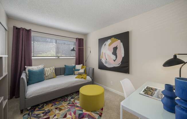 a living room with a couch and a desk in front of a window