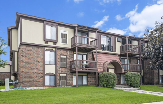 a brick apartment building with balconies and a green lawn at Apple Ridge Apartments, Michigan, 49534