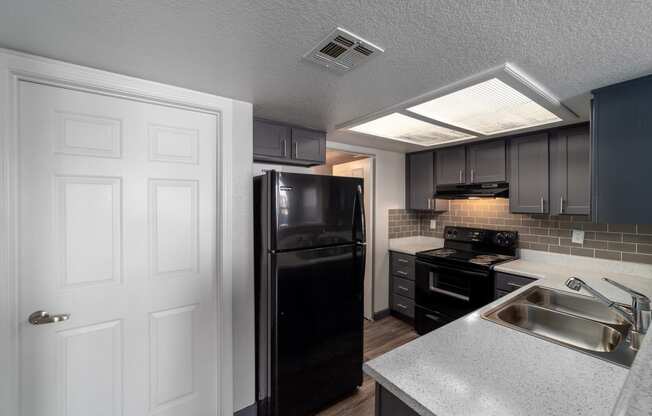 a kitchen with a sink and a black refrigerator