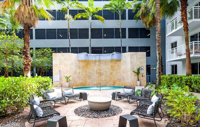A patio with a fire pit surrounded by chairs and plants.