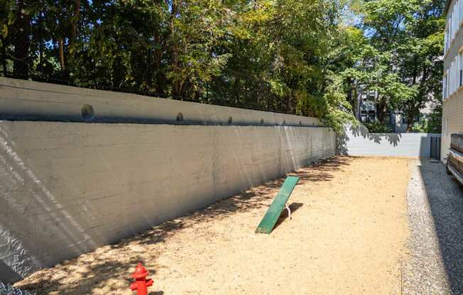 a red fire hydrant sitting in the sand next to a fence