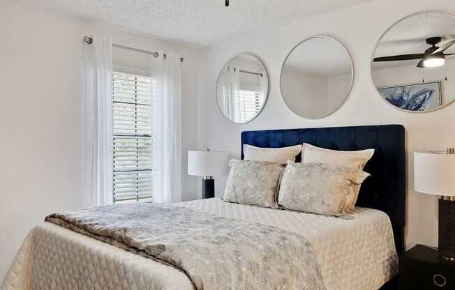 a bedroom with a bed and two mirrors above it at The Lorient Apartments, Florida