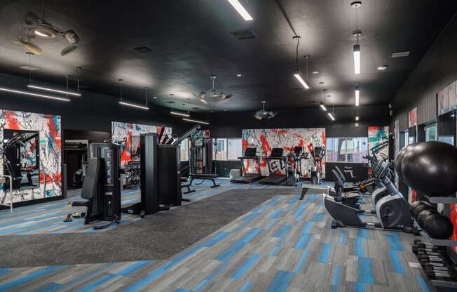 a fitness room with weights and other exercise equipment and a wall of graffiti