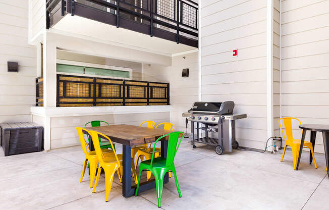 a patio with a table and chairs and a grill