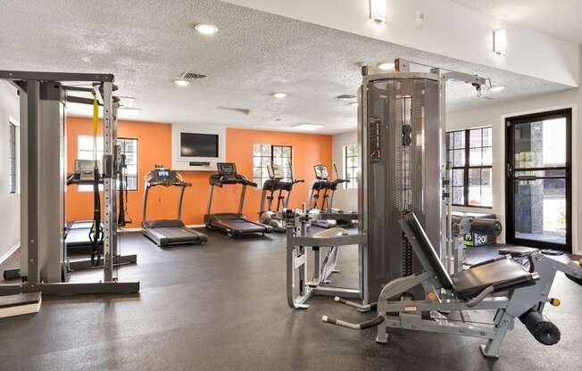 a gym with cardio equipment and weights on the floor