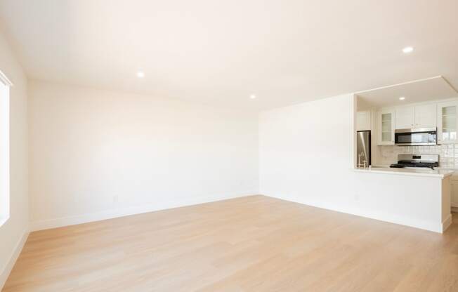 an empty living room with white walls and a wood floor