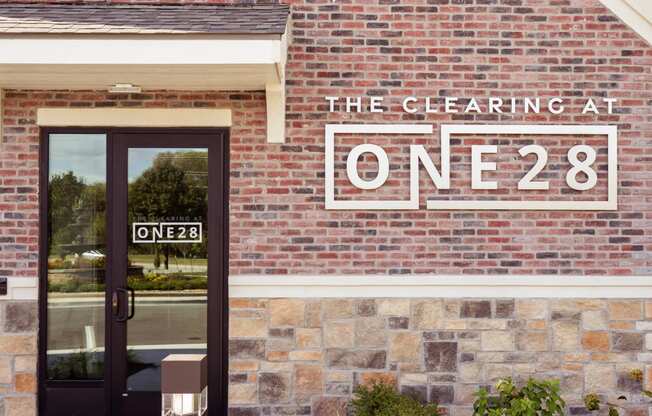 the facade of a brick building with a sign that reads the clearing at one 82  at The Clearing at ONE28, Olathe, Kansas