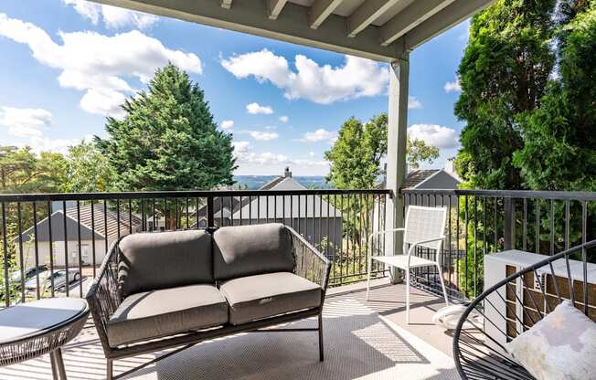 A patio with a couch, chair, and table with a view of the mountains.