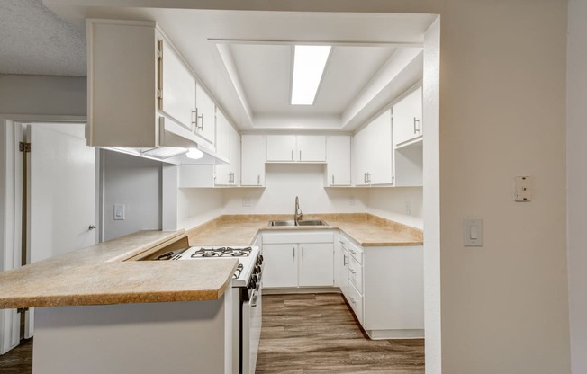 an empty kitchen with white cabinets and a counter top