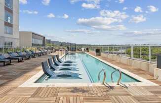 A large outdoor pool with wooden decking and lounge chairs.