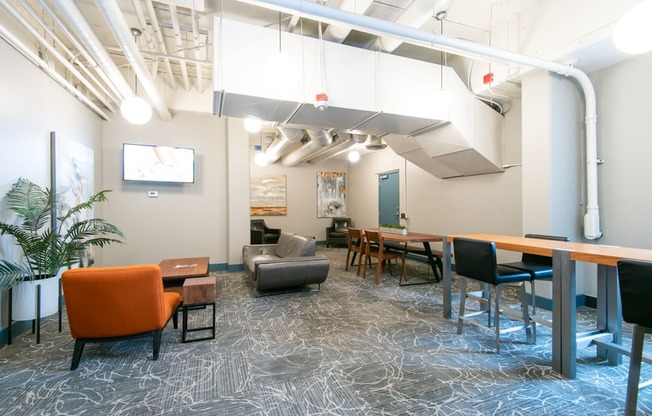 A modern office space with a patterned carpet and a mix of orange and black furniture.