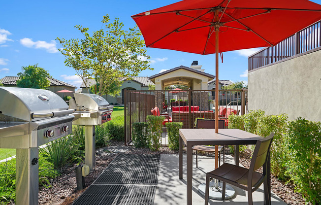a patio with an umbrella and a table with chairs and a grill