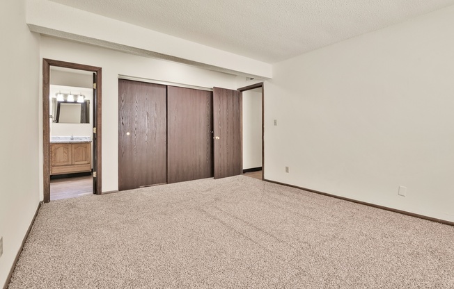 A bedroom with a carpeted floor and a large closet with a mirror.