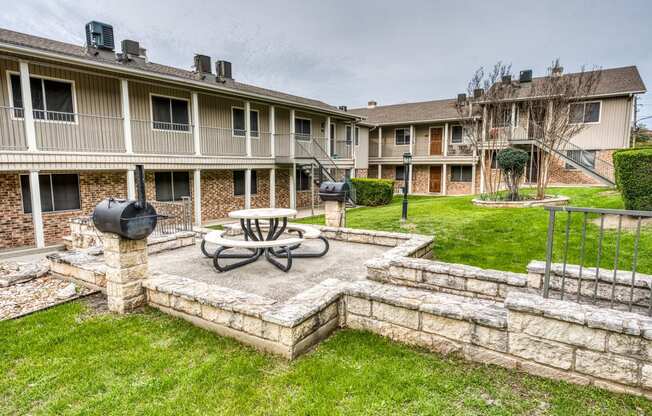 a patio with a table and a fire pit in front of an apartment building