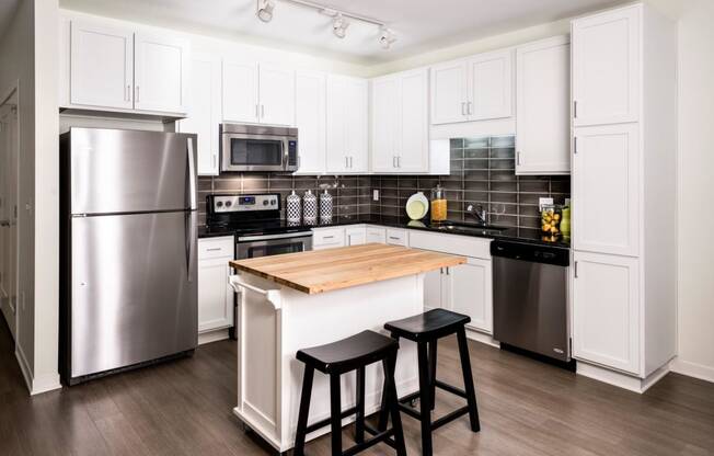 Kitchen with small central island, white cabinets finishes and stainless steel appliances