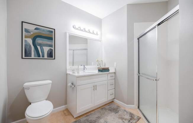 a white bathroom with a white toilet and a glass shower