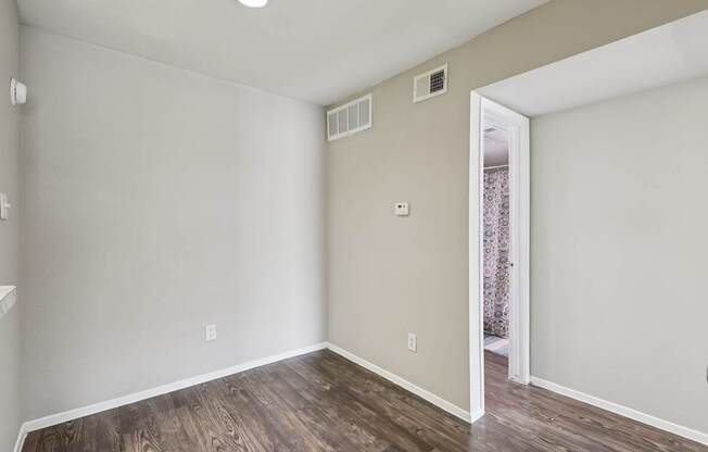A room with wooden flooring and a doorway leading to another room.