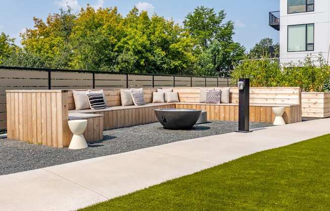 a patio with a wooden bench and a fire pit in front of a fence