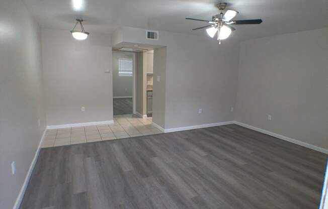an empty living room with wooden floors and a ceiling fan