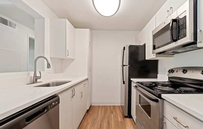 A kitchen with black appliances and white cabinets.