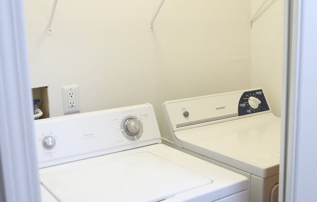a white washer and dryer in a white laundry room with white walls at Evergreen Luxury Apartments, Merrillville, 46410