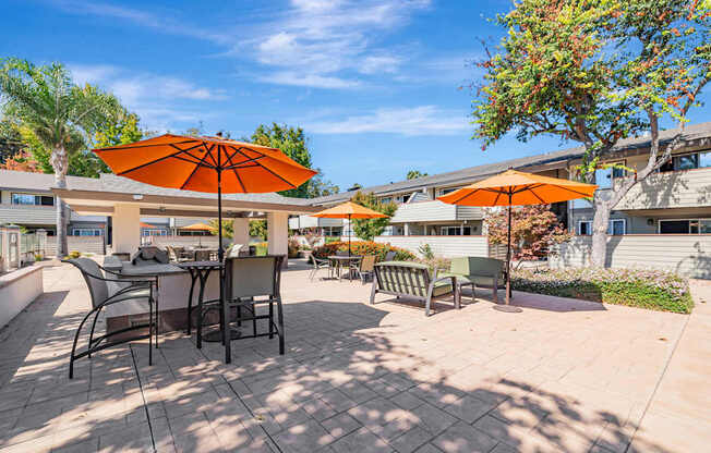 A patio with orange umbrellas and chairs.